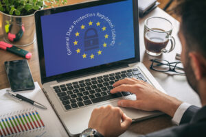 man working with a computer, general data protection regulation and european union flag on the screen